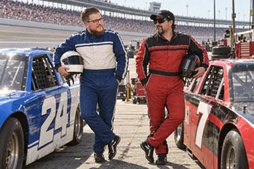 Aaron Rountree in a blue racing suit beside the number 24 stock car and Andrew Lee Jenkins in a red racing suit beside the number 7 car